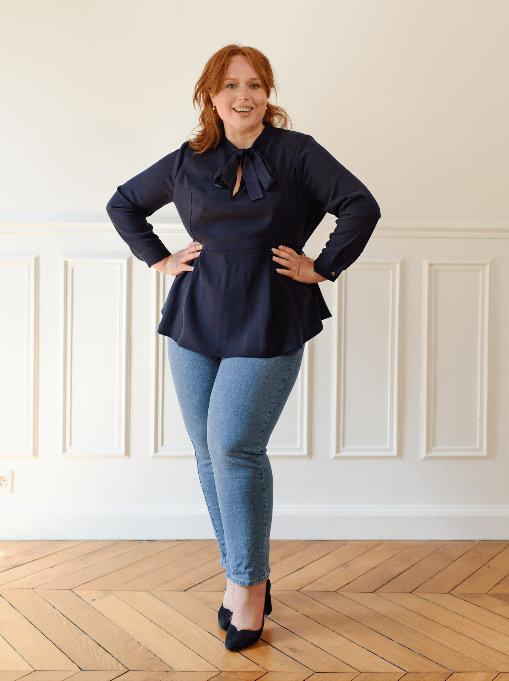 Woman wearing a blue crepe blouse with peplum fall and neck tie blouse is looking at us